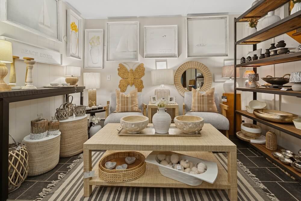 showroom sitting area with two chairs, shelving, coffee and console tables and home accents