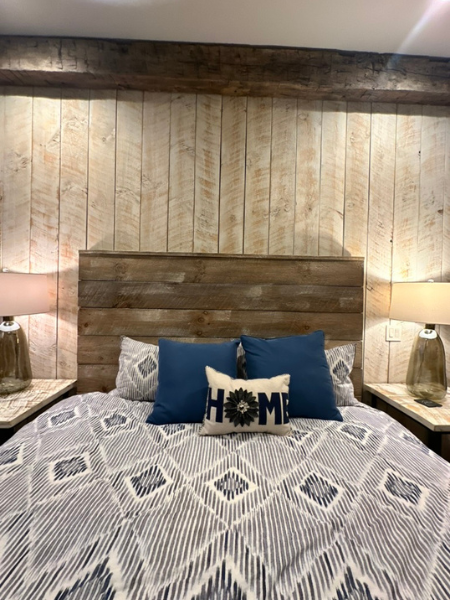 Queen bed headboard against whitewashed wood paneling