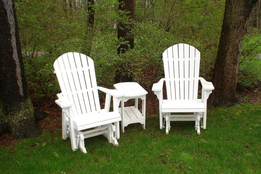 Two white adirondack gliders and oblong side table