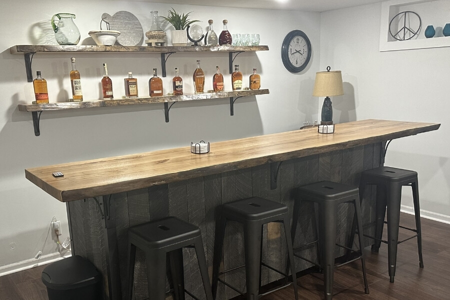 Reclaimed wood bar with matching shelves holding liquor behind